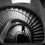 Escalier hélicoïdal en noir et blanc, silhouette descendant les marches — illustration de la courbe du changement