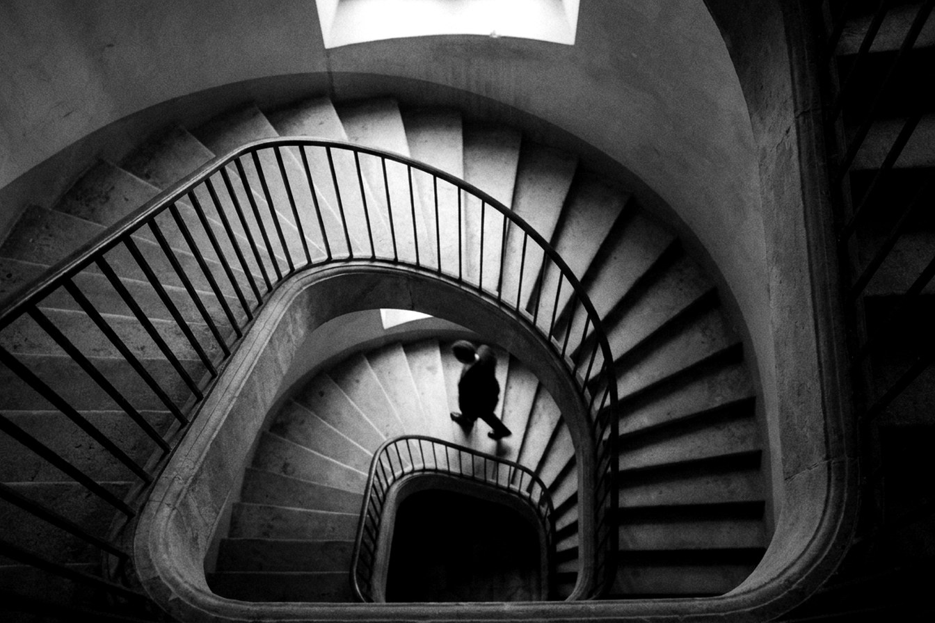 Escalier hélicoïdal en noir et blanc, silhouette descendant les marches — illustration de la courbe du changement