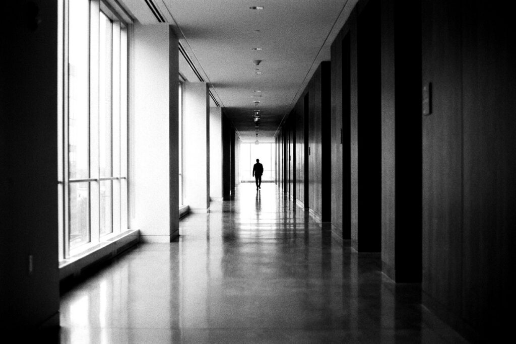 Long couloir de siège social en noir et blanc, silhouette au loin — modèle ADKAR