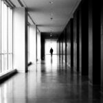 Long couloir de siège social en noir et blanc, silhouette au loin — modèle ADKAR