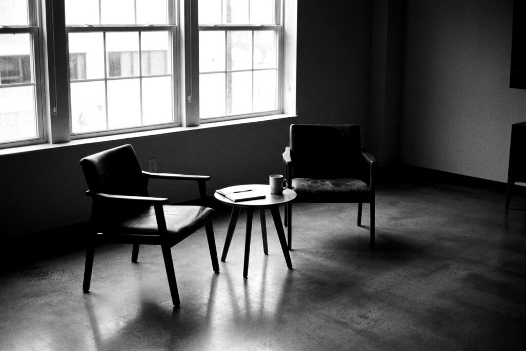 Deux fauteuils vides face à face dans une salle de réunion en noir et blanc — change management