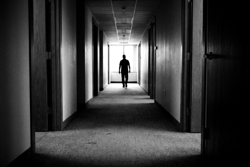 Long couloir de bureaux en noir et blanc, silhouette au loin — démarche GEPP