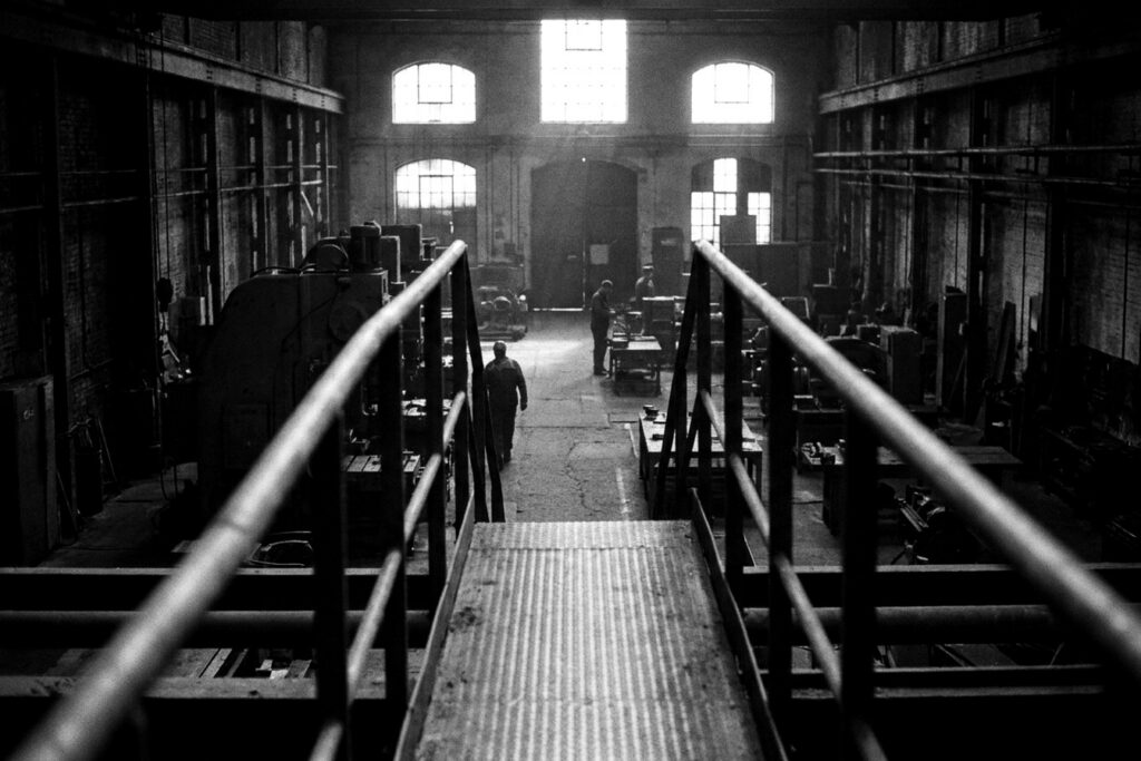 Passerelle industrielle en noir et blanc surplombant un atelier — accompagnement au changement
